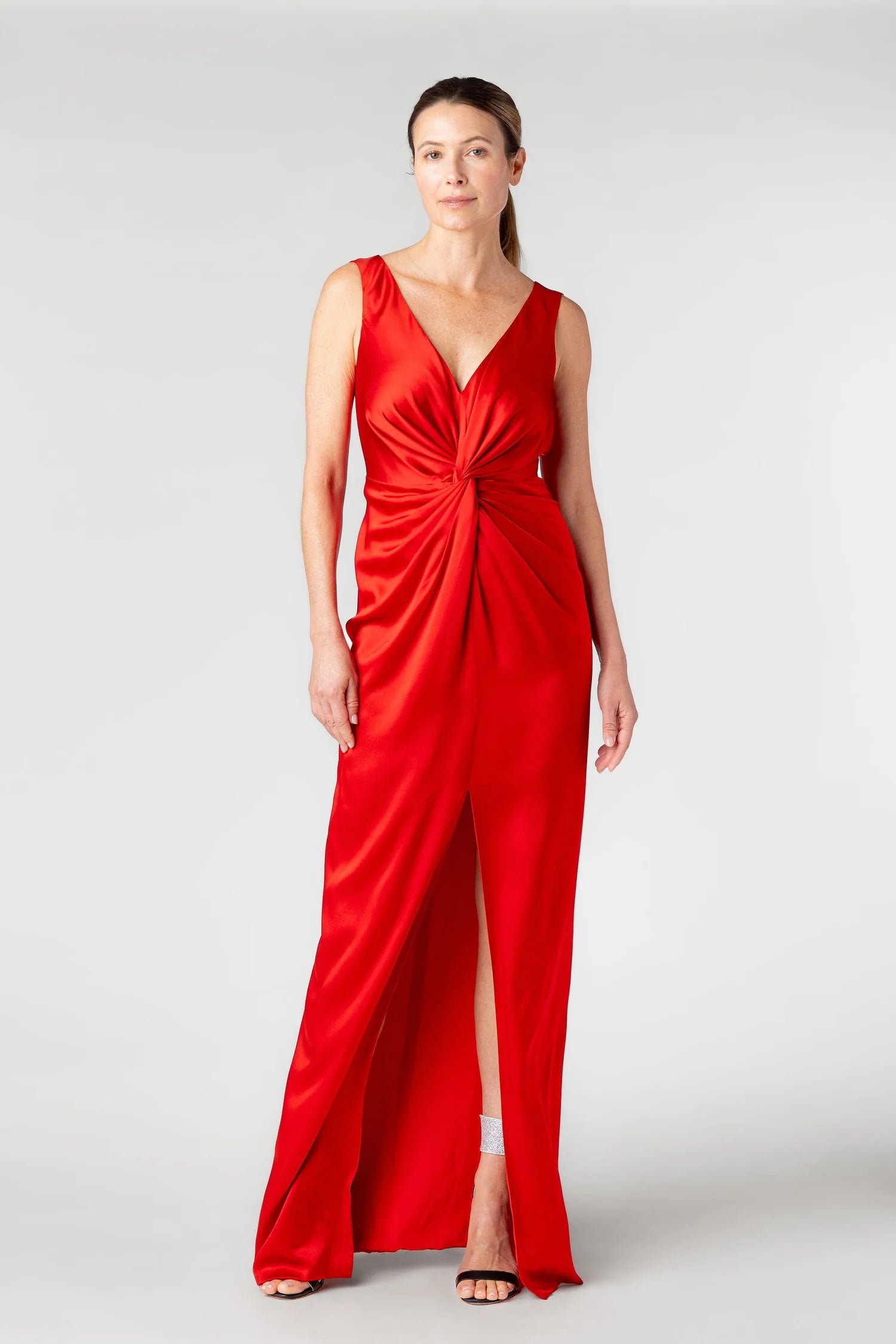 Woman wearing a red dress with a deep neckline and slit on a white background